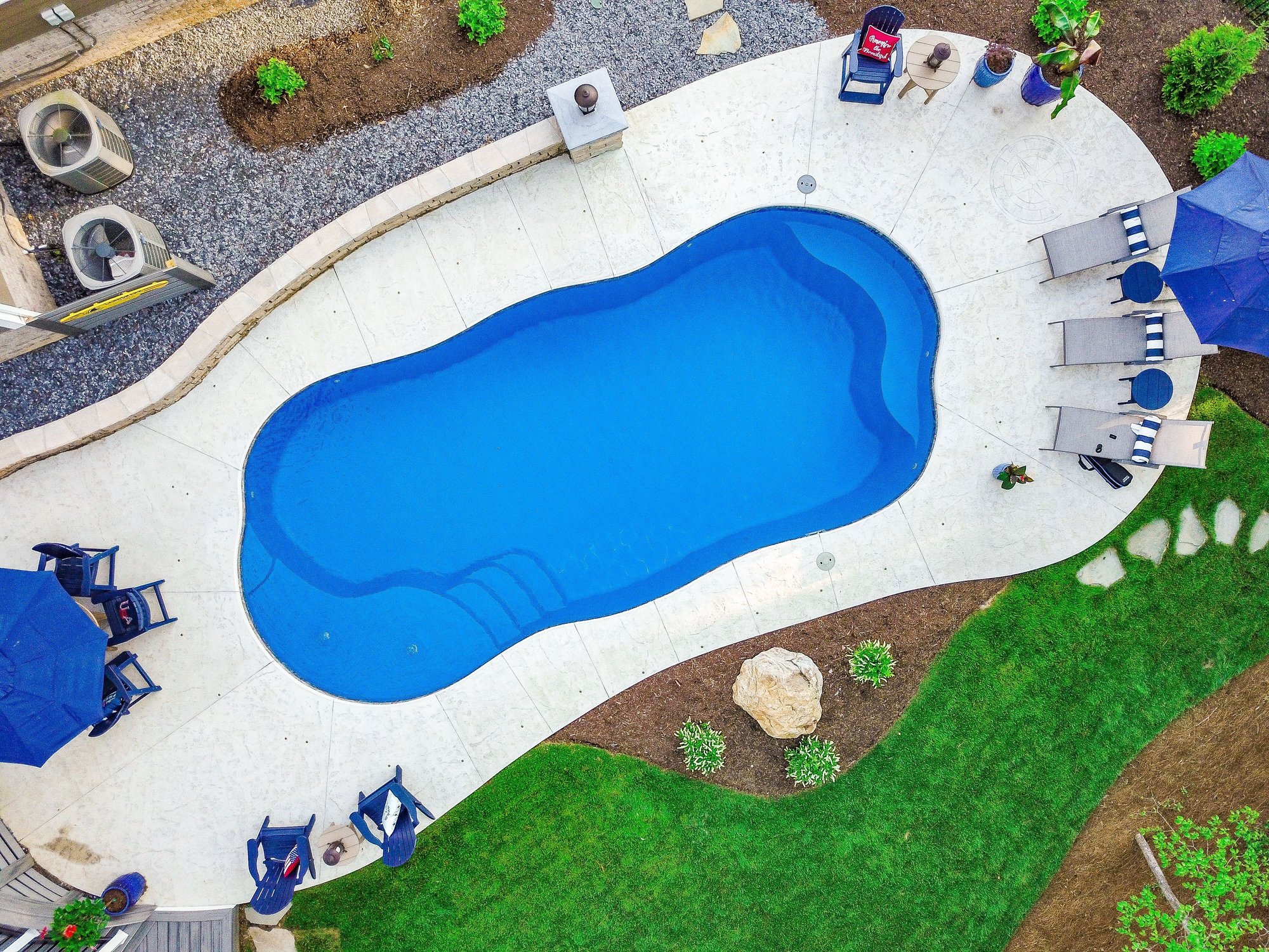 River Pools C35 with white stone coping and patio furniture overlooking a fresh sod backdrop.